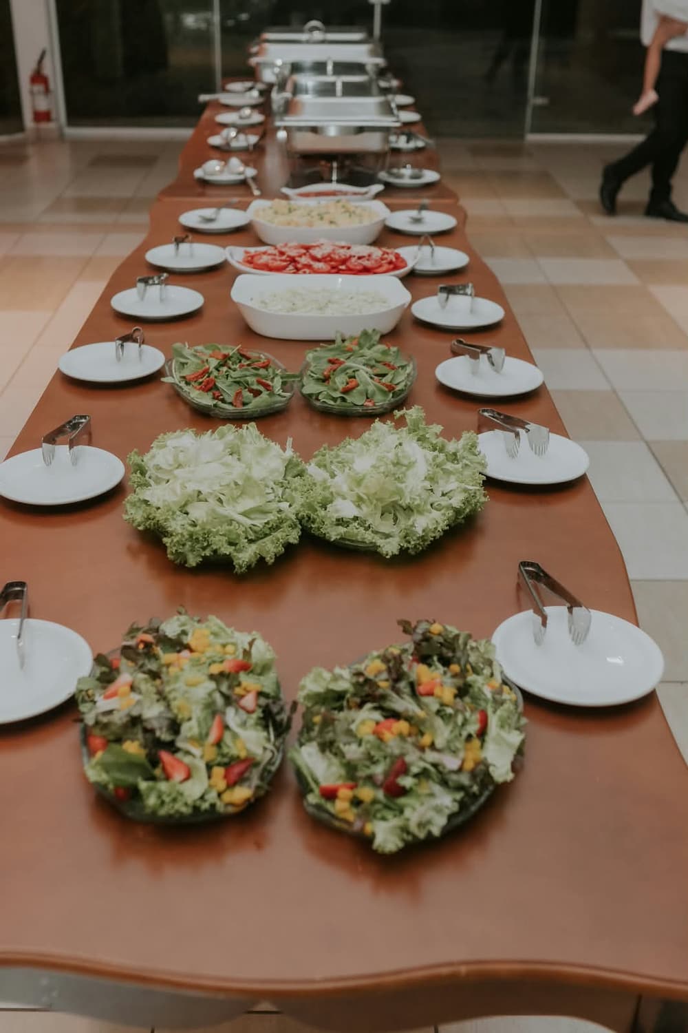 Mesa comprida do buffet montada com saladas e entradas em travessas