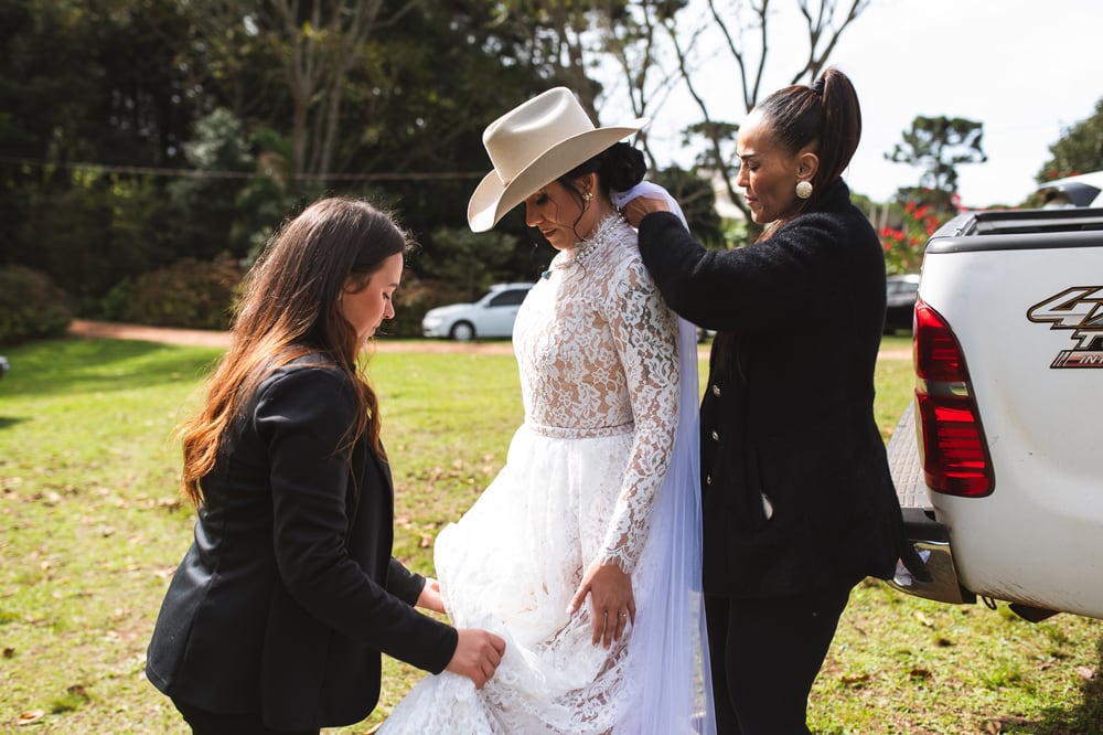 Duas cerimonialistas ajeitando o vestido da noiva antes da entrada